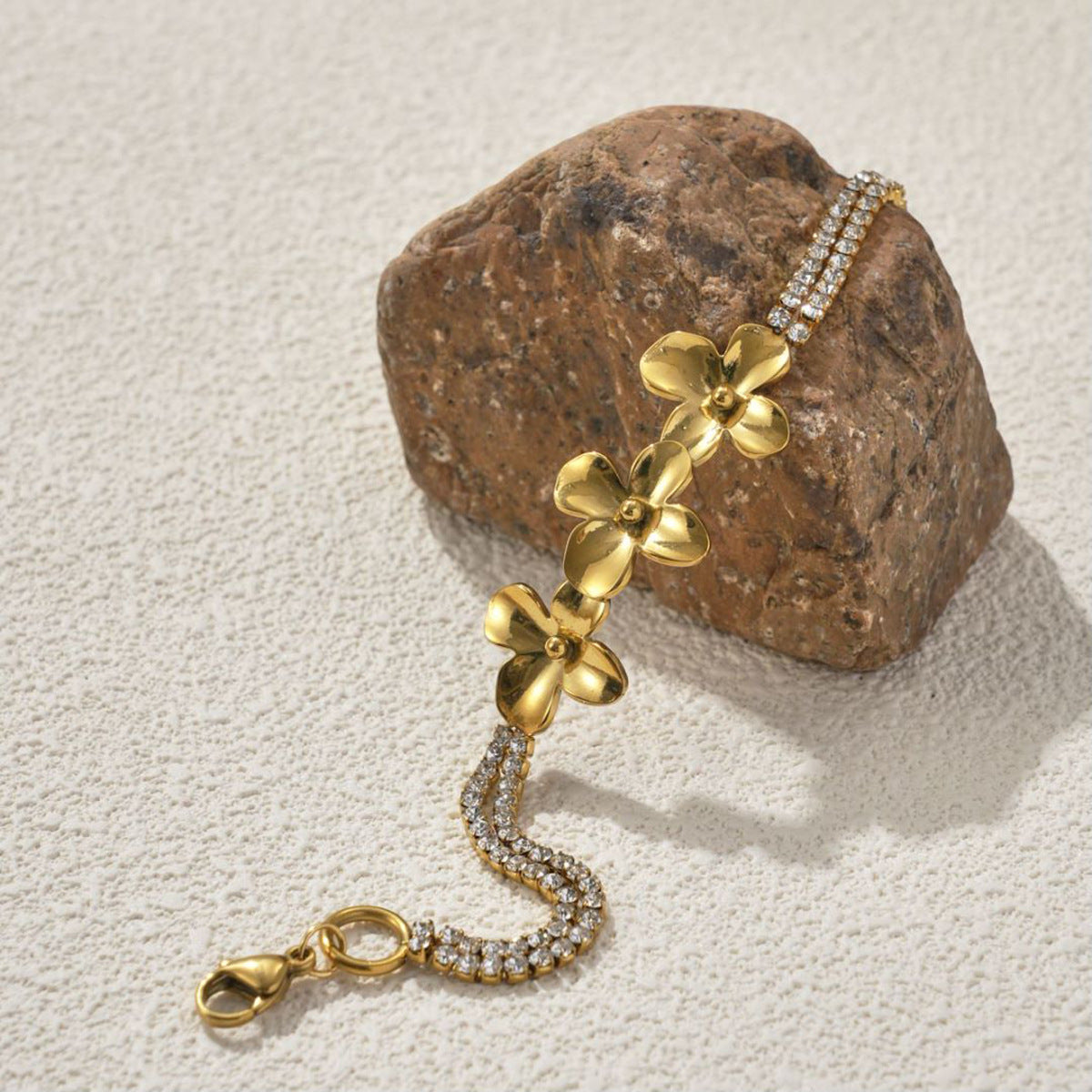 Gold tone flower bracelet leaning on a stone