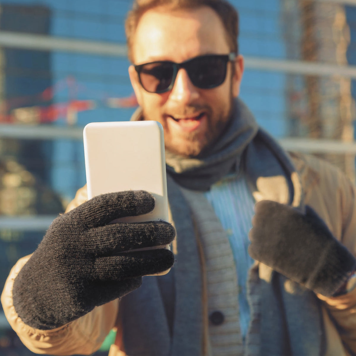 Black knit gloves holding a phone outdoors