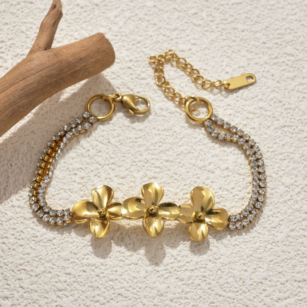 Gold tone flower bracelet with a crystal strand on wood