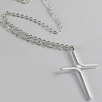 Silver tone cross pendant on a chain, close view