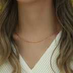 Gold tone chain necklace worn with a V neck top