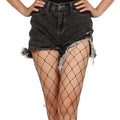 Close-up of black fishnet tights under distressed denim shorts