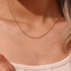 Dainty gold tone chain necklace worn at the neck