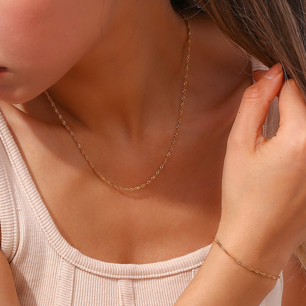 Gold tone chain necklace worn at the collarbone