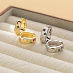 Huggie hoop earrings with colored stones in a ring dish