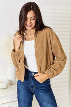 Camel jacket worn open over a white tee with hand in pocket