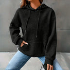 Black waffle knit hoodie with drawstring hood, worn with jeans